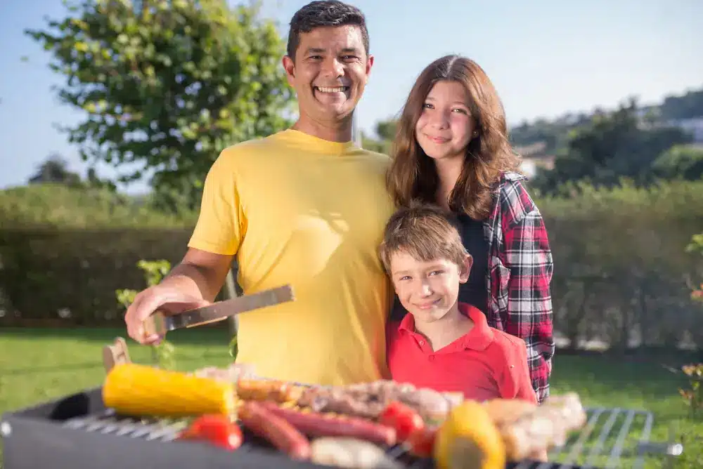 The Importance of Professional Gas Line Installation for Outdoor BBQs - Happy family in front of a BBQ grill.