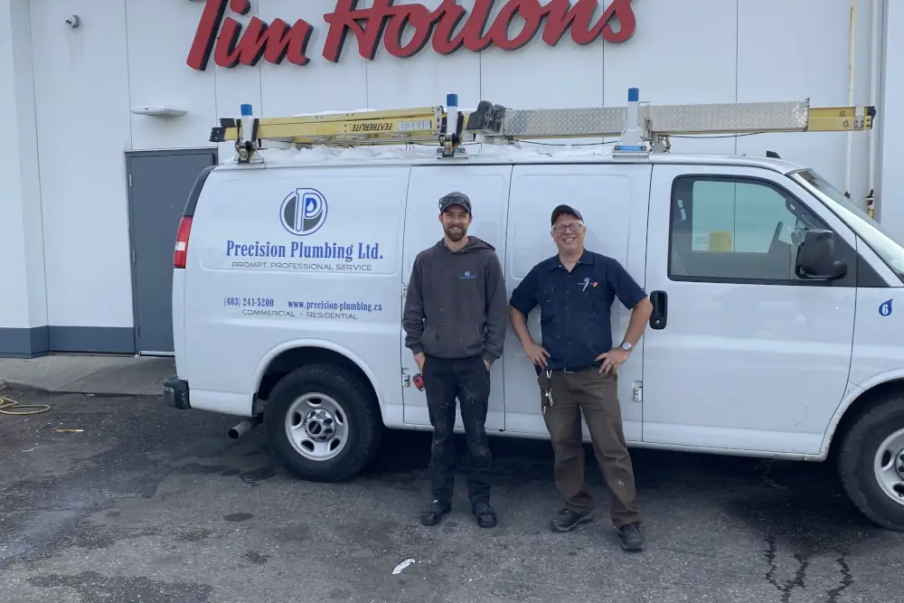 15 years plumbing service celebration - 2 employees standing in front of the company van