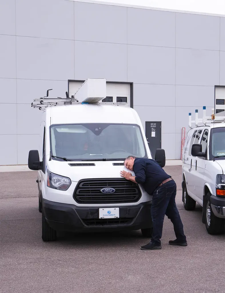 Precision plumbing team member hugging service vehicle