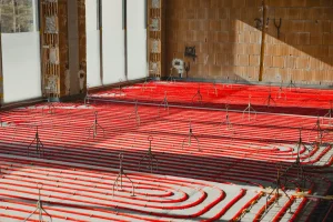 Installing underfloor heating system in new building with red pipes